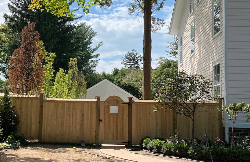 Wood privacy fence with arched gate in a landscaped yard